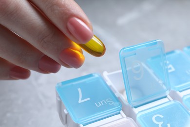 Photo of Woman putting pill into plastic box, closeup view