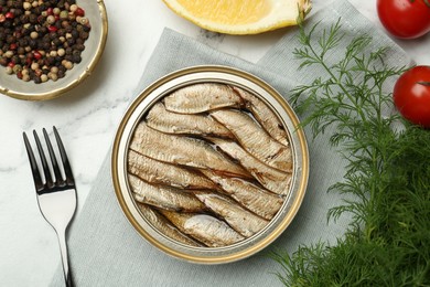 Photo of Tin can with tasty sprats served on white marble table, flat lay