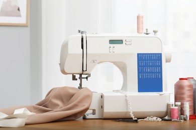 Photo of Sewing machine with fabric and craft accessories on wooden table indoors