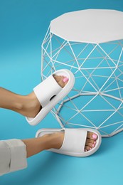 Photo of Woman wearing comfortable rubber slippers on light blue background, closeup