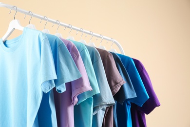 Photo of Men's clothes hanging on wardrobe rack against light background