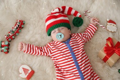 Photo of Cute little baby with Christmas candy cane sleeping on fluffy blanket, view from above
