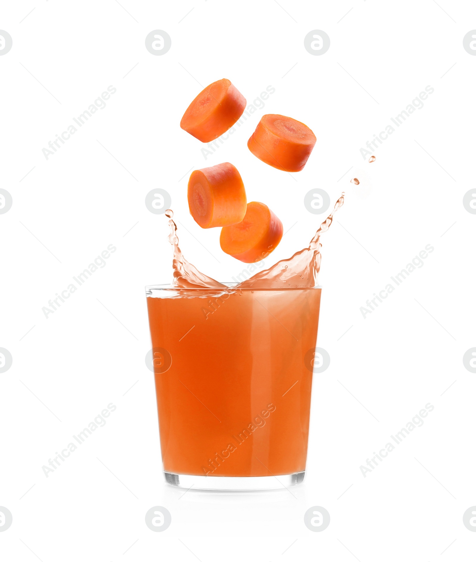 Image of Splashing freshly made carrot juice on white background. Cut carrot falling into glass