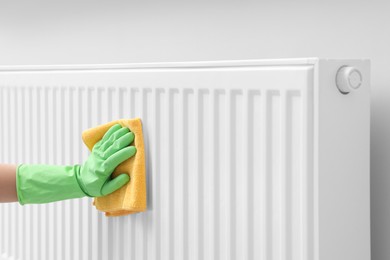 Photo of Woman cleaning radiator with rag indoors, closeup. Space for text