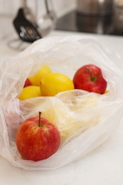 Plastic bags with different fresh products on white countertop indoors