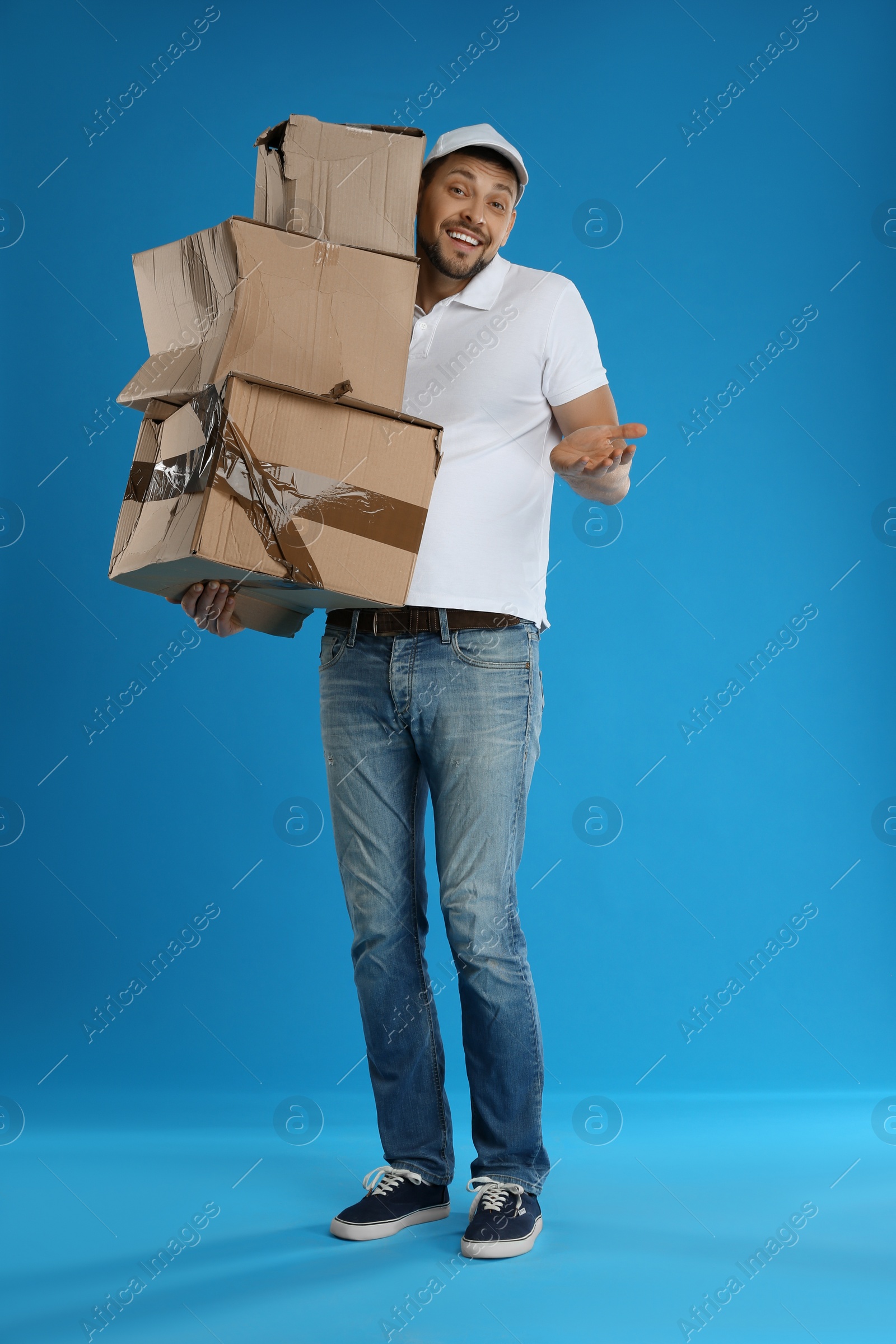 Photo of Emotional courier with damaged cardboard boxes on blue background. Poor quality delivery service