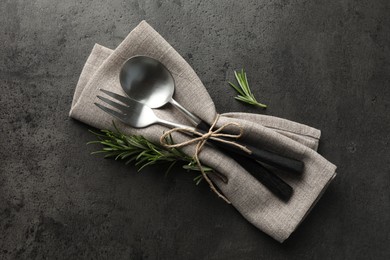 Stylish setting with cutlery and napkin on black table, top view