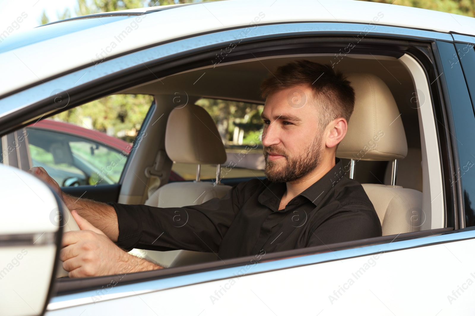 Photo of Handsome young driver sitting in modern car