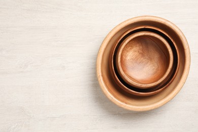 Photo of Empty clean wooden dishware on white table, top view. Space for text