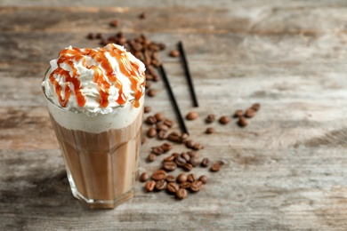 Photo of Glass of coffee with caramel topping on wooden background