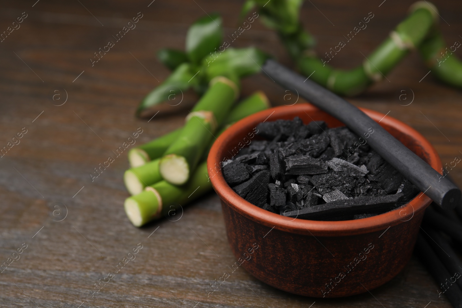 Photo of Fresh bamboo and charcoal on wooden table, closeup. Space for text