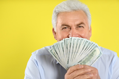 Photo of Emotional senior man with cash money on yellow background