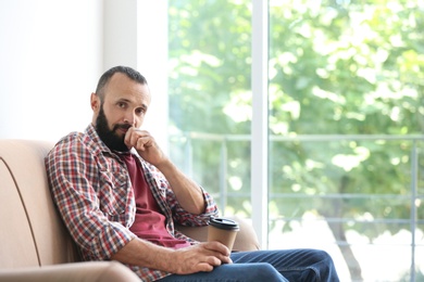 Portrait of handsome mature man with coffee on sofa at home