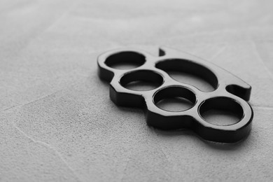 Photo of Black brass knuckles on grey stone background, closeup. Space for text