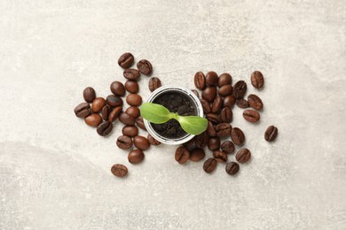 Photo of Coffee capsule with seedling and beans on light grey table, flat lay
