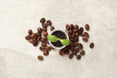 Coffee capsule with seedling and beans on light grey table, flat lay