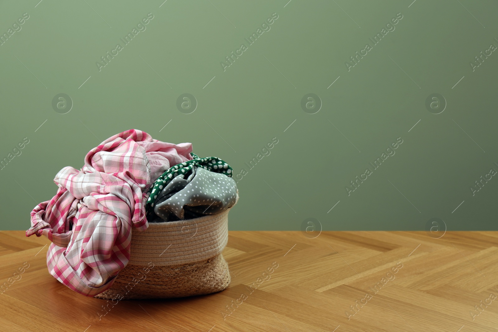 Photo of Laundry basket with clothes near light green wall. Space for text