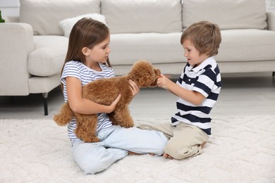 Photo of Little children playing with cute puppy on carpet at home. Lovely pet