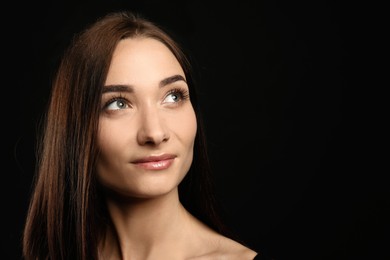 Portrait of pretty young woman with gorgeous chestnut hair on black background, space for text