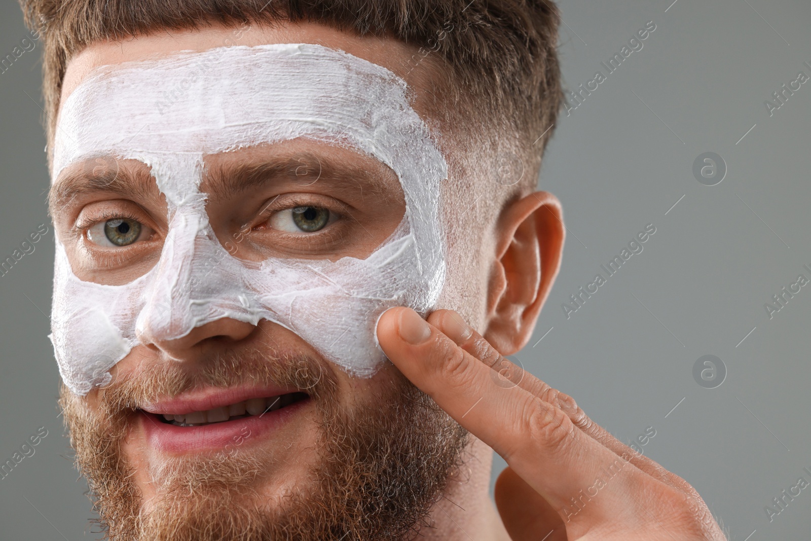 Photo of Handsome man with facial mask on his face against grey background