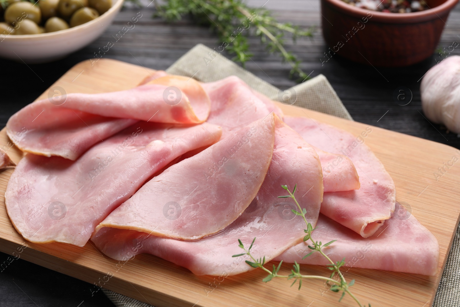 Photo of Slices of delicious ham with thyme on table, closeup