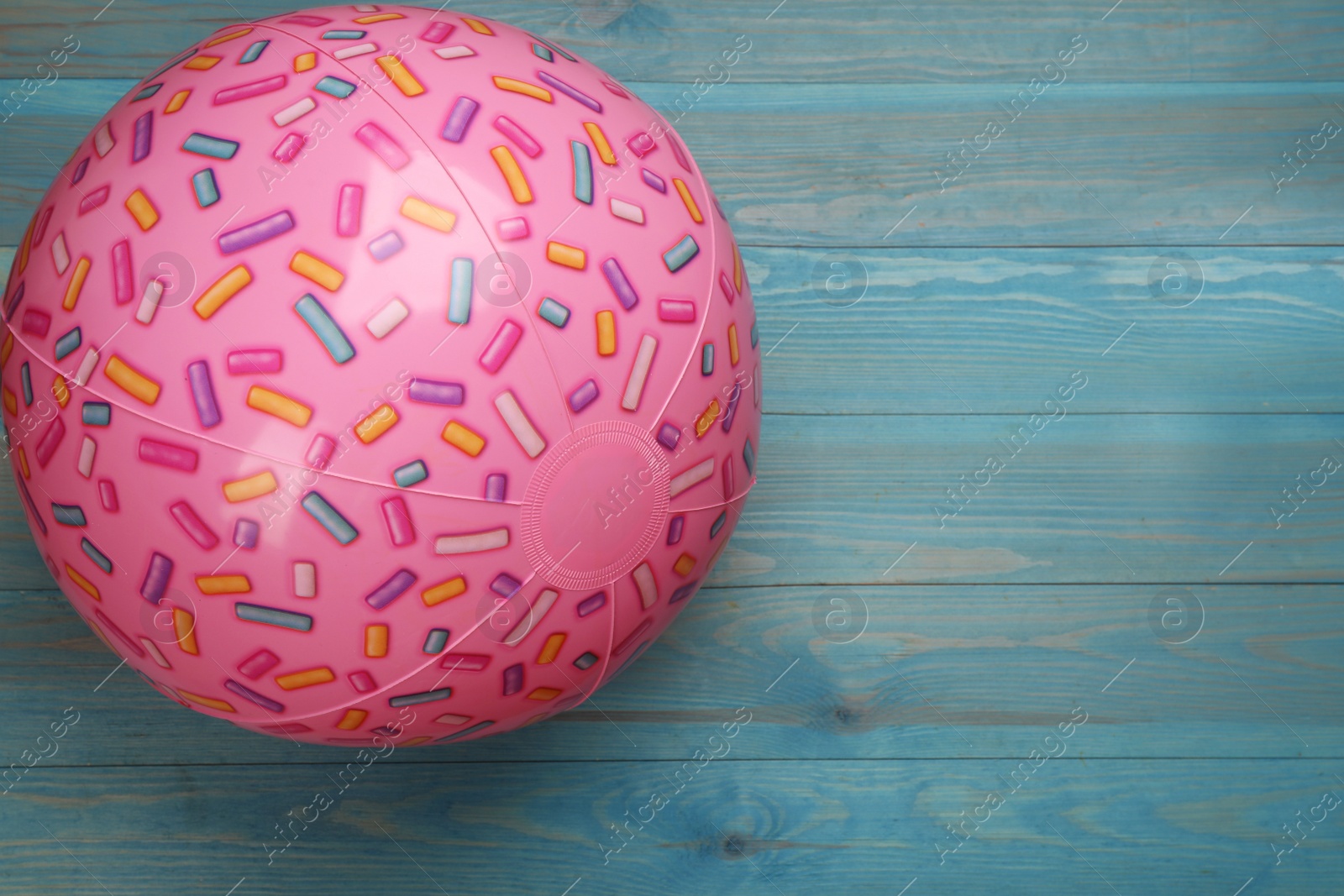 Photo of Pink beach ball on light blue wooden background, top view. Space for text