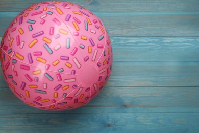Photo of Pink beach ball on light blue wooden background, top view. Space for text