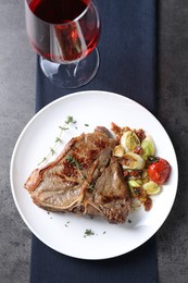 Photo of Delicious fried beef meat, vegetables and wine on grey table, top view