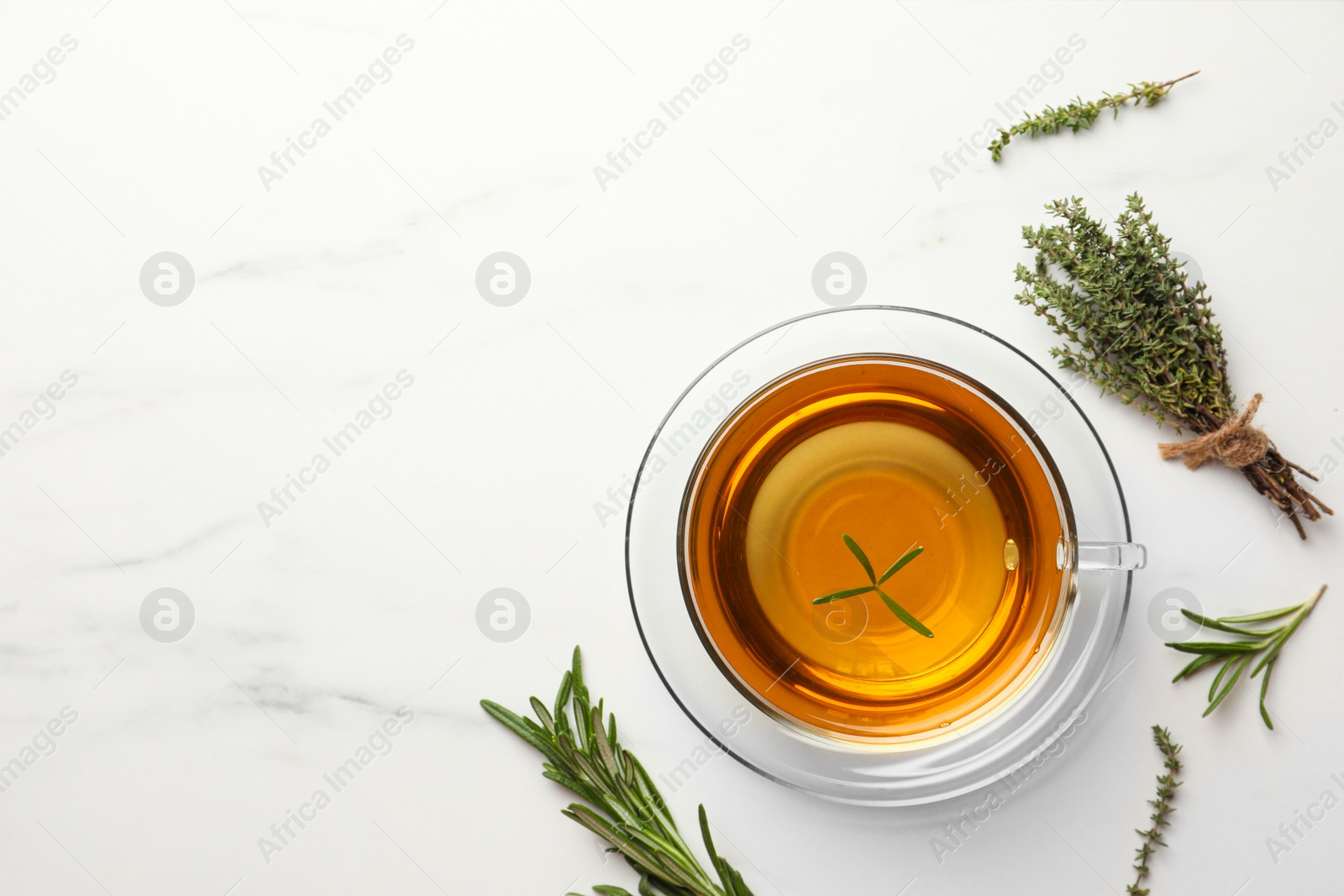 Photo of Cup of aromatic herbal tea with thyme and rosemary on white marble table, flat lay. Space for text