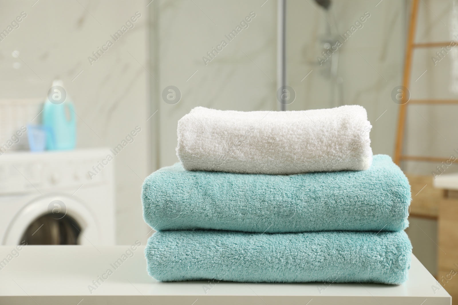 Photo of Stack of clean towels on table in laundry room