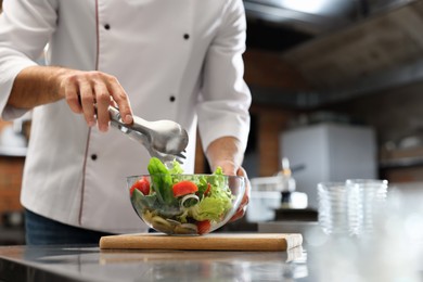 Professional chef making salad in restaurant kitchen, closeup