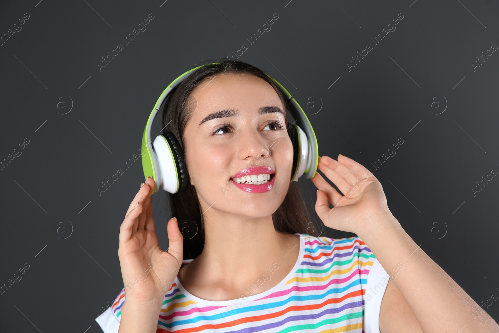 Photo of Beautiful young woman listening to music with headphones on black background