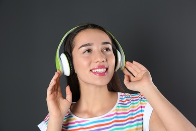 Photo of Beautiful young woman listening to music with headphones on black background