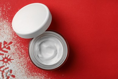 Photo of Winter skin care. Hand cream and artificial snow on red background, top view. Space for text