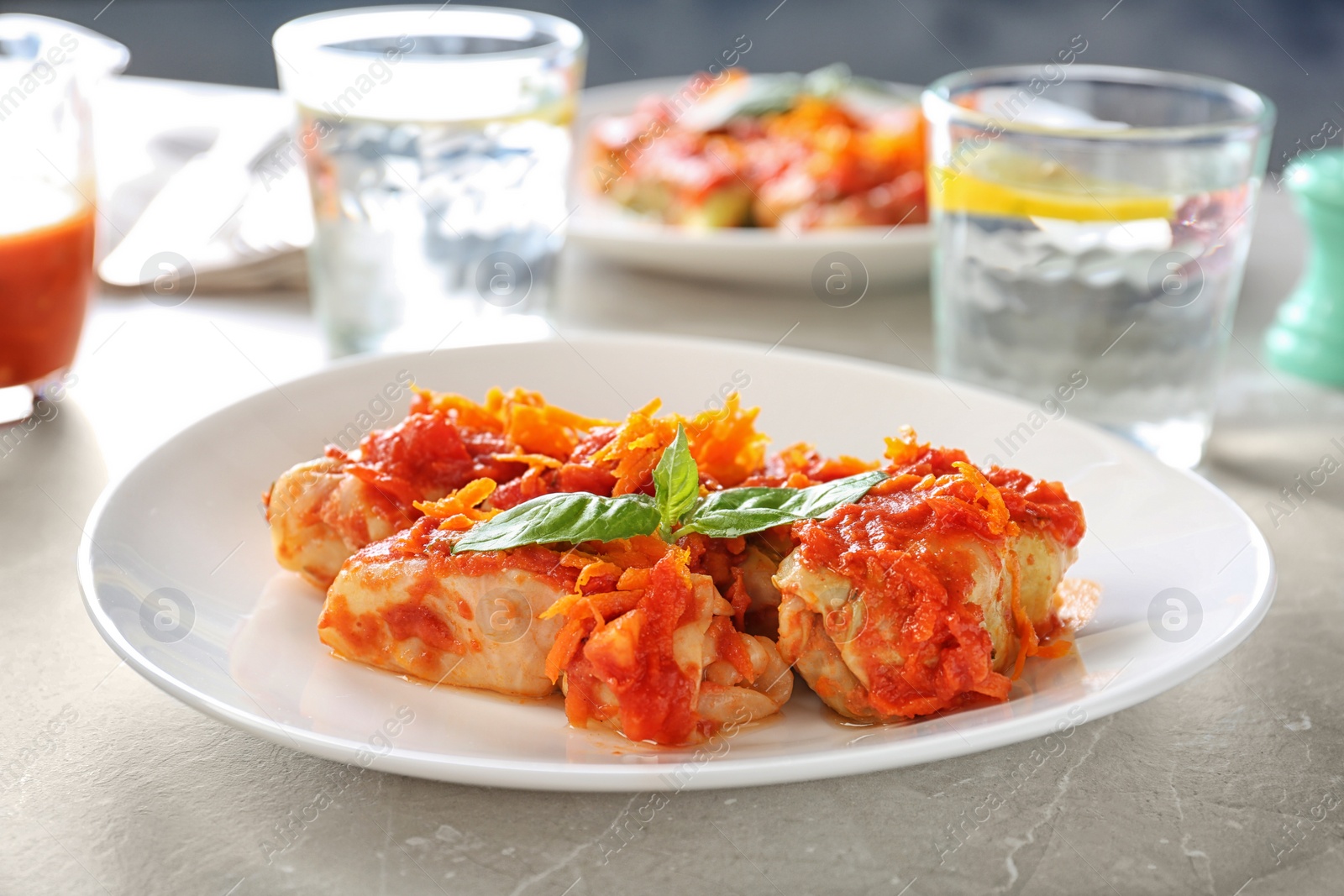 Photo of Plate with stuffed cabbage leaves in tomato sauce on table