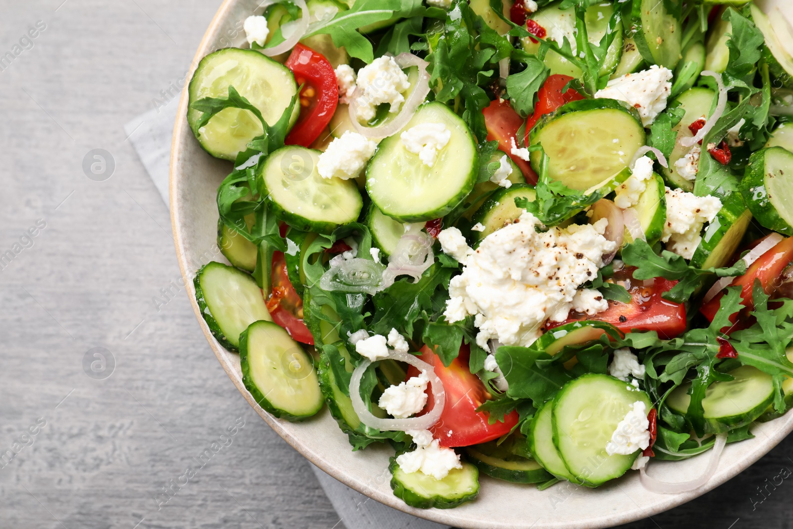 Photo of Plate of delicious cucumber salad on grey table, top view