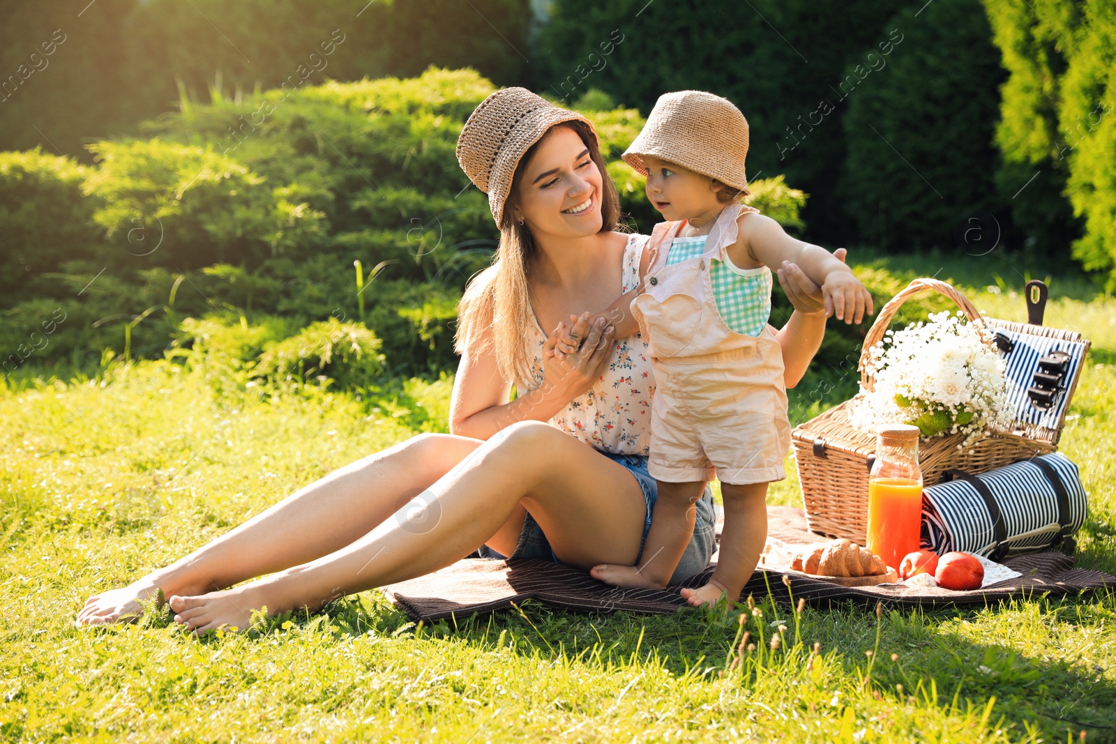 Photo of Mother with her baby daughter having picnic in garden on sunny day