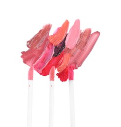 Photo of Strokes of different lip glosses and applicators isolated on white, top view
