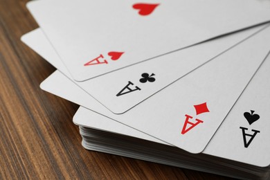 Photo of Four aces playing cards on wooden table, closeup