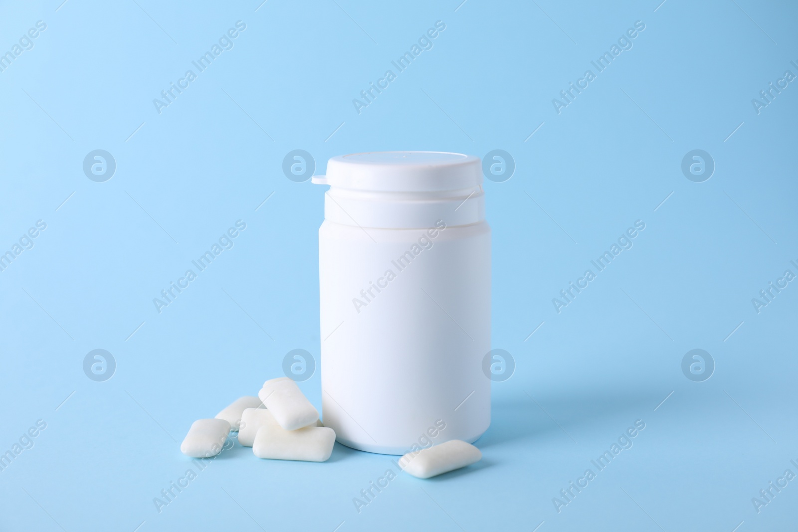 Photo of Jar with tasty chewing gums on light blue background