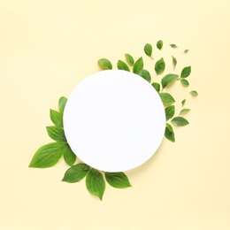 Photo of Flat lay composition with blank card and spring green leaves on color background. Space for text