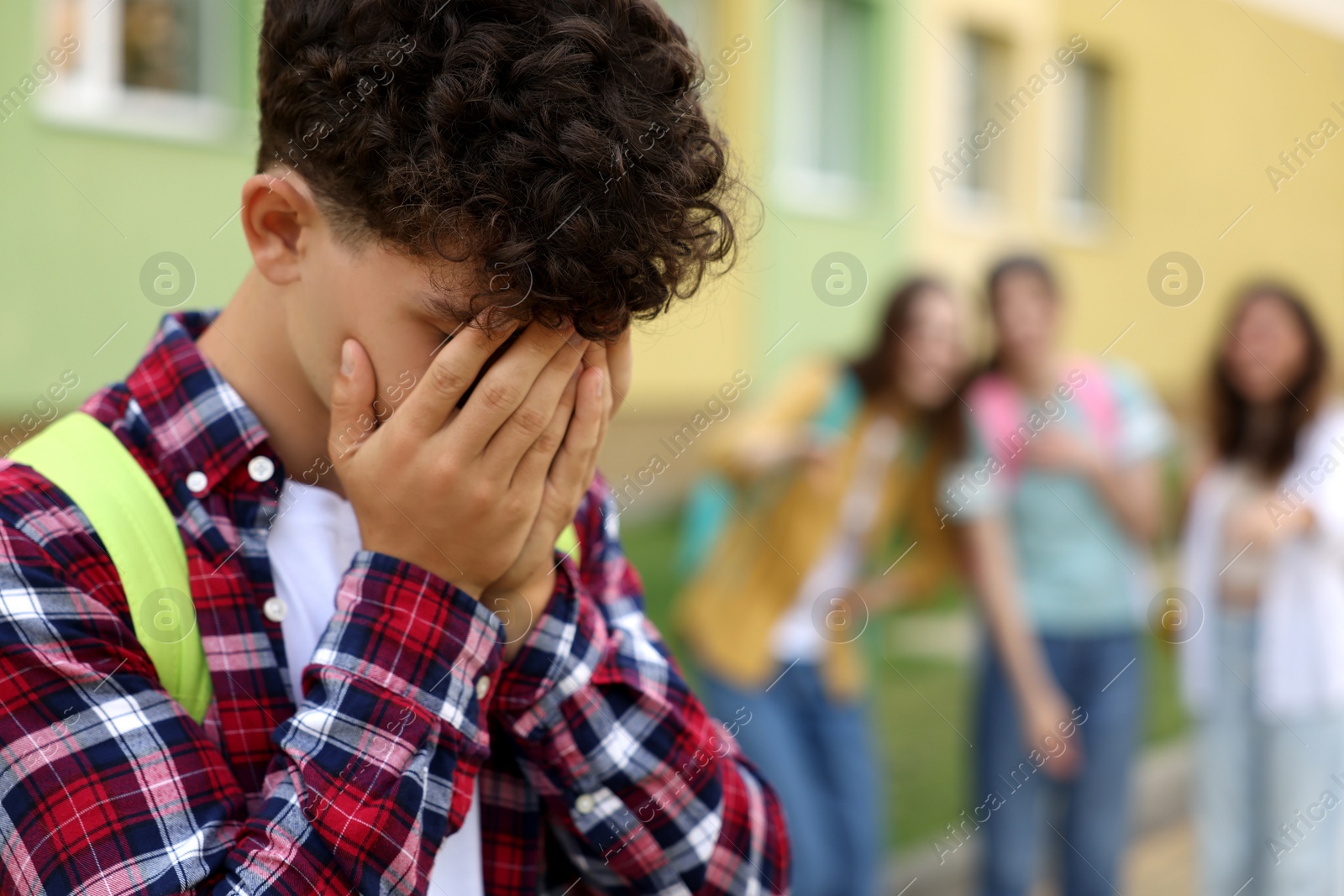 Photo of Teen problems. Group of students pointing at upset boy outdoors, selective focus