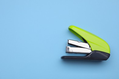 Photo of New bright stapler on light blue background, top view. Space for text