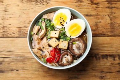 Bowl of delicious ramen on wooden table, top view. Noodle soup