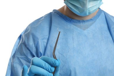 Doctor holding needle with suture thread on white background, closeup. Medical equipment