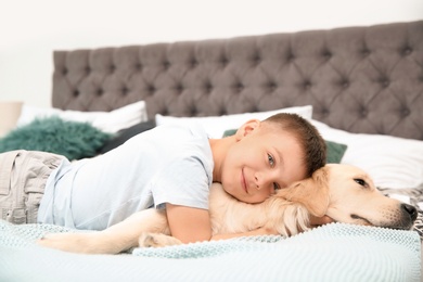 Cute little child with his pet on bed at home