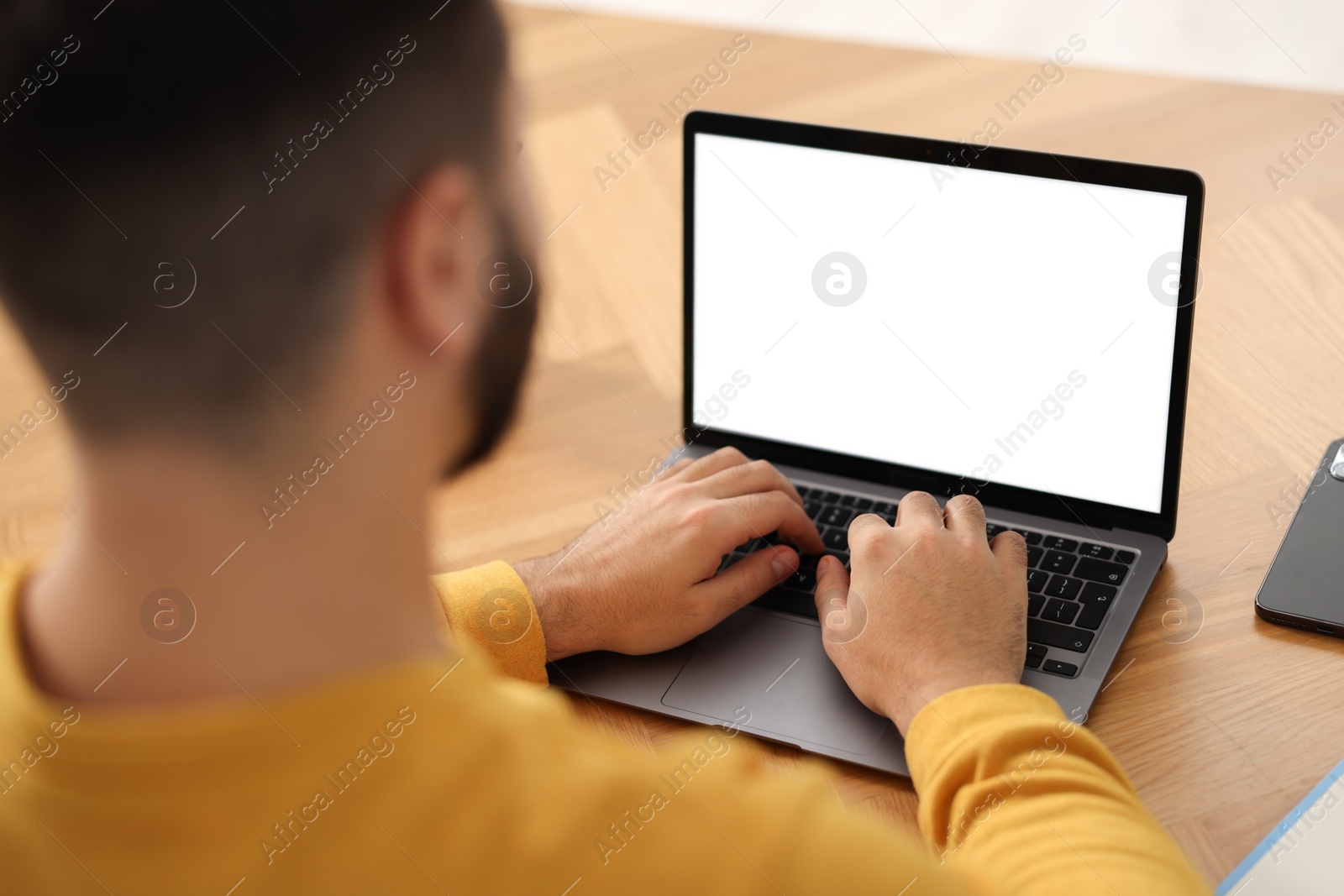 Photo of Young man watching webinar at table, closeup