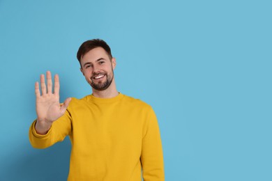 Man giving high five on light blue background. Space for text