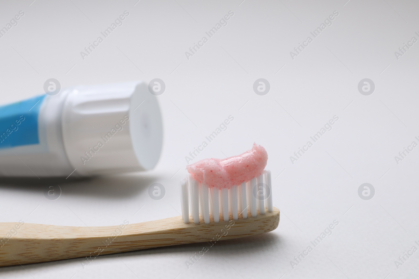 Photo of Brush with toothpaste and tube on white background, closeup