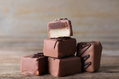 Tasty milk chocolate candies on wooden table, closeup